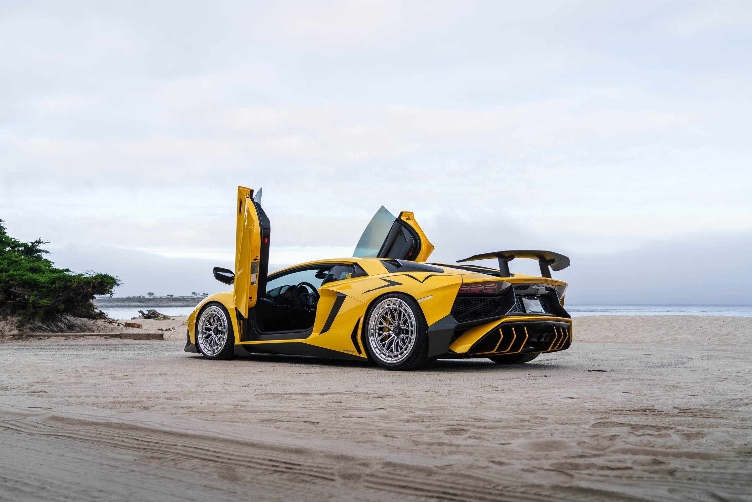 Yellow Lamborghini Aventador SV with scissor doors on a beach